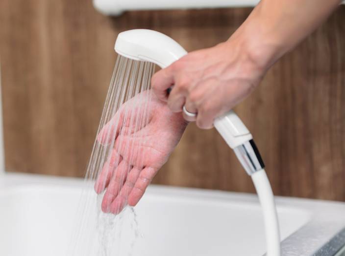 入浴介助のため水温を確認しているスタッフの手元写真