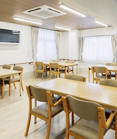 4人がけの机が4つ並んでいるリビングスペースの内観写真